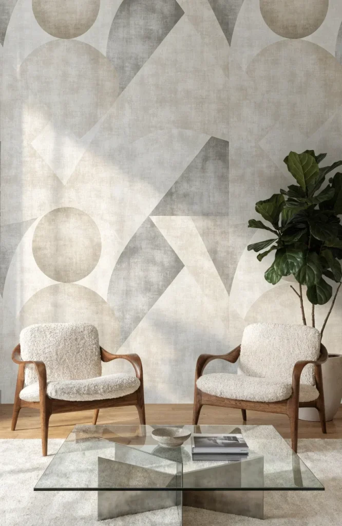 A modern living room with neutral geometric wallpaper, mid-century chairs, and a glass coffee table.