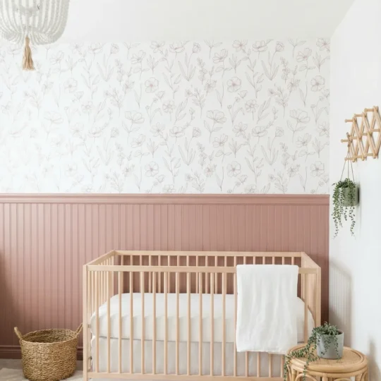 A modern Boho nursery featuring a minimalist botanical Floral Wallpaper above dusty rose wainscoting, with a baby crib and rattan furniture.