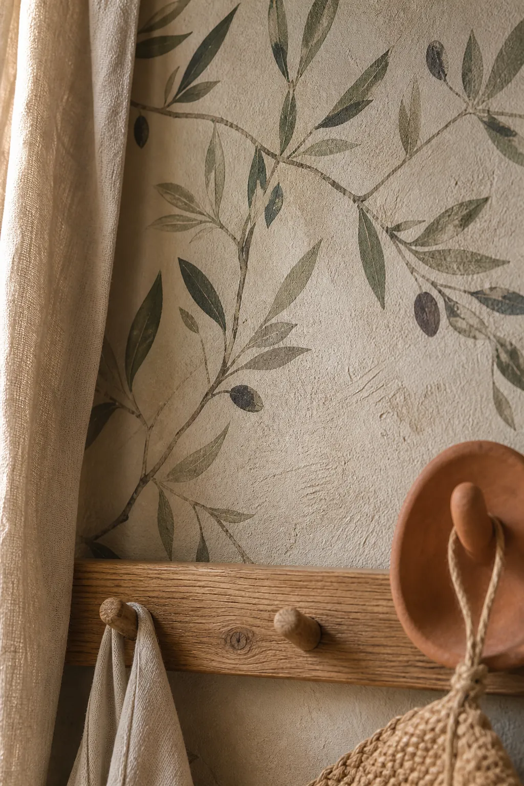 Close view of olive branch wall mural texture with matte neutral surface and linen beside it