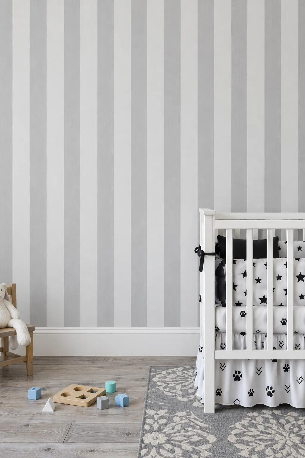 Nursery pairing gray and white striped walls with a white crib.